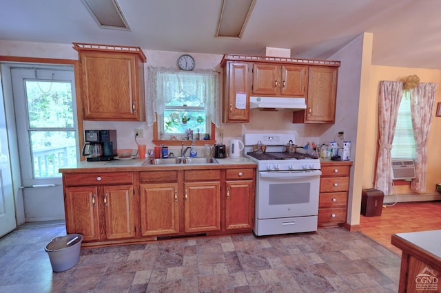 kitchen featuring under cabinet range hood, plenty of natural light, a sink, and white gas stove