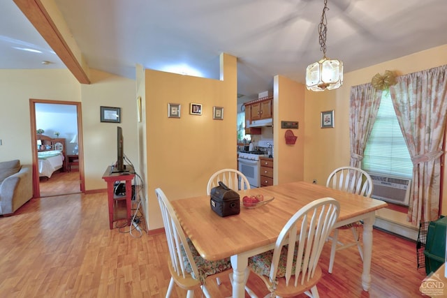 dining room featuring light wood-style floors, cooling unit, vaulted ceiling with beams, and baseboards