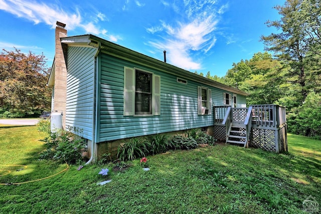 view of home's exterior with a chimney, a lawn, and a wooden deck