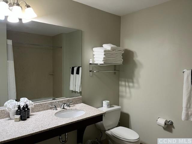 bathroom with a chandelier, a shower with shower curtain, toilet, and sink