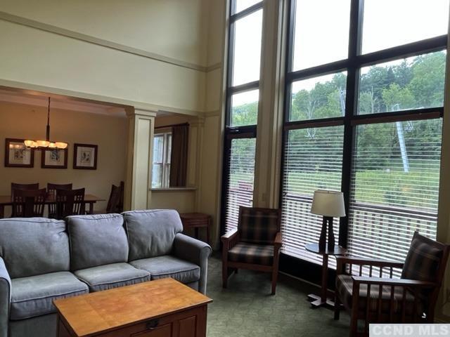 carpeted living room with plenty of natural light, decorative columns, and a chandelier