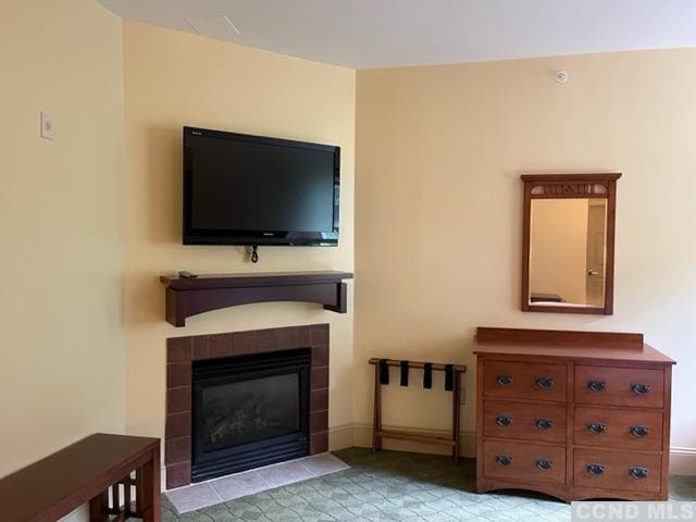 unfurnished living room featuring a tiled fireplace and light carpet