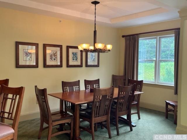 dining space featuring an inviting chandelier, a wealth of natural light, and a tray ceiling