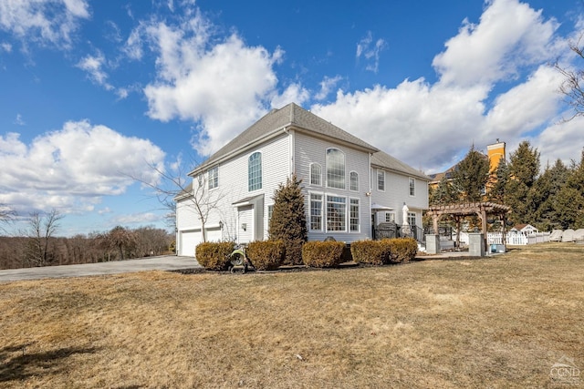 view of side of property with a garage, a lawn, driveway, and a pergola