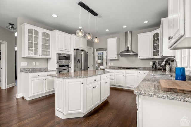 kitchen featuring a sink, dark wood-type flooring, white cabinets, appliances with stainless steel finishes, and wall chimney range hood
