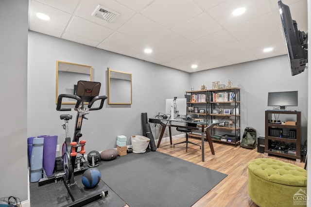 workout area featuring visible vents, a paneled ceiling, baseboards, and wood finished floors