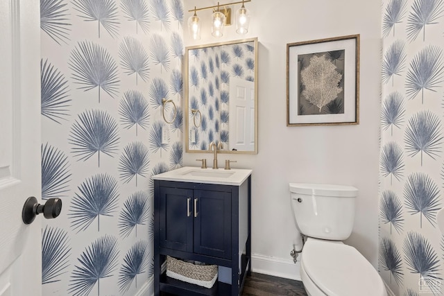 bathroom featuring baseboards, toilet, wood finished floors, and vanity