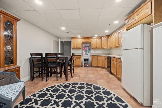 kitchen with light tile patterned floors, freestanding refrigerator, light countertops, black dishwasher, and a paneled ceiling