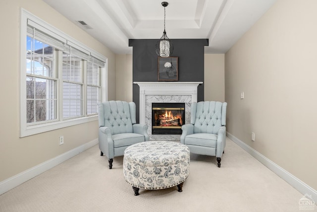 sitting room featuring a high end fireplace, visible vents, baseboards, carpet flooring, and a raised ceiling