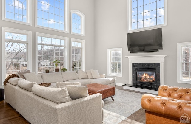living room featuring a fireplace, baseboards, and a towering ceiling