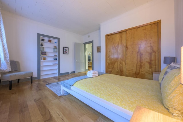 bedroom featuring a closet, ornamental molding, and wood finished floors