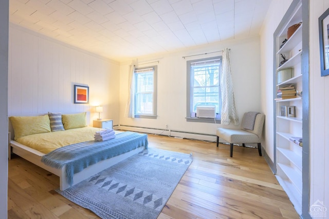 bedroom featuring hardwood / wood-style flooring, baseboard heating, and ornamental molding