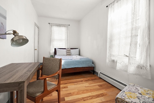 bedroom with baseboard heating and light wood-style flooring