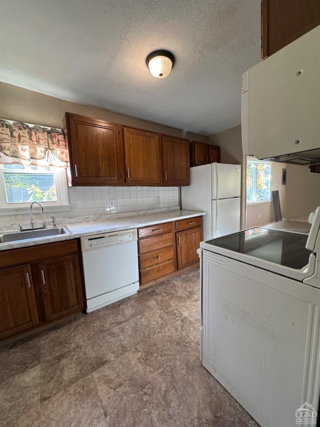 kitchen featuring white appliances, backsplash, plenty of natural light, and sink