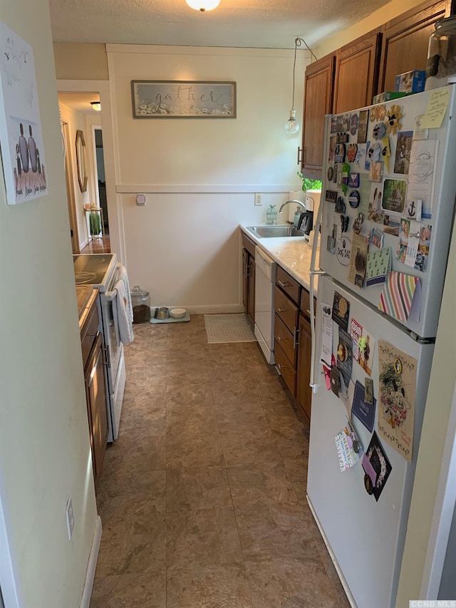 kitchen with a textured ceiling, white appliances, and sink