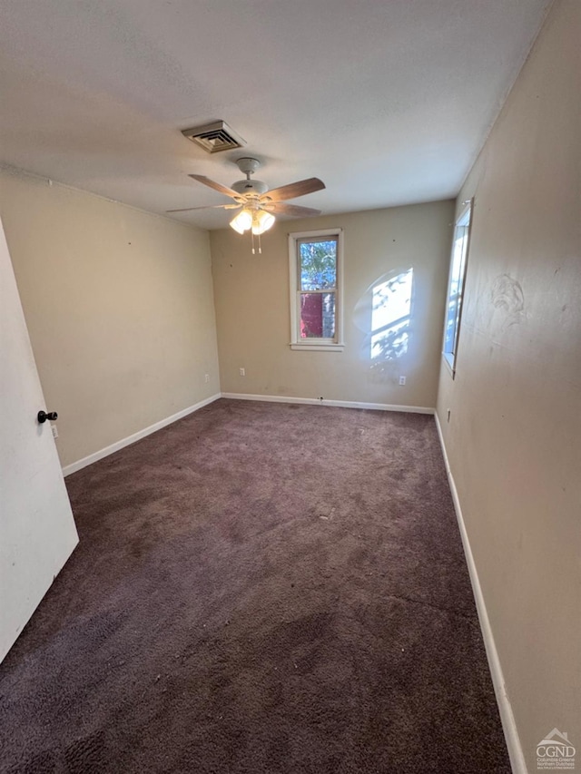 spare room with ceiling fan and dark colored carpet