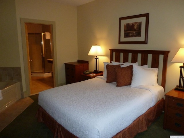 bedroom with ensuite bathroom and dark carpet