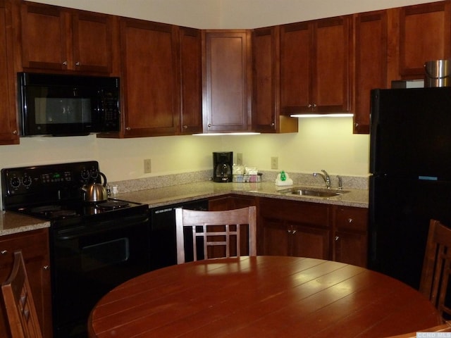 kitchen featuring black appliances, light stone countertops, and sink