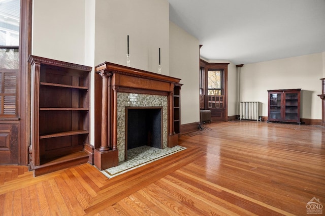 unfurnished living room with a tiled fireplace and radiator heating unit