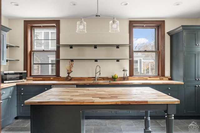 kitchen featuring pendant lighting, butcher block countertops, sink, and a center island