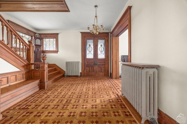 foyer featuring radiator, a notable chandelier, and french doors