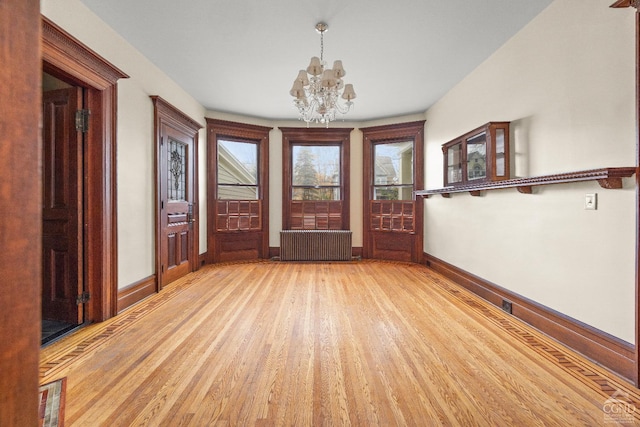 unfurnished room with a notable chandelier, radiator heating unit, and light wood-type flooring