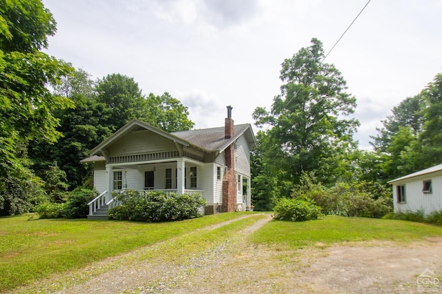 view of side of property featuring a porch and a yard