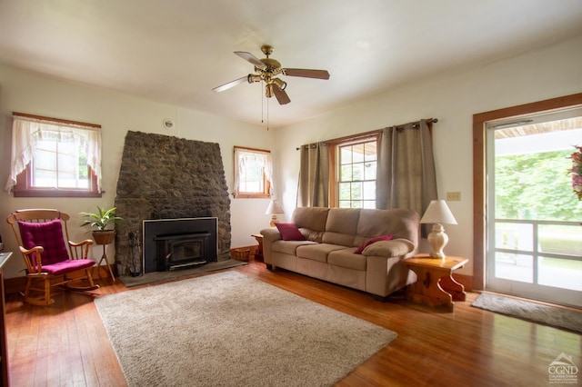 living room featuring hardwood / wood-style floors, a wood stove, ceiling fan, and a healthy amount of sunlight