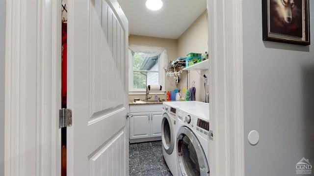 clothes washing area with washing machine and clothes dryer, sink, and cabinets