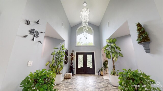 entrance foyer featuring a notable chandelier, high vaulted ceiling, and french doors