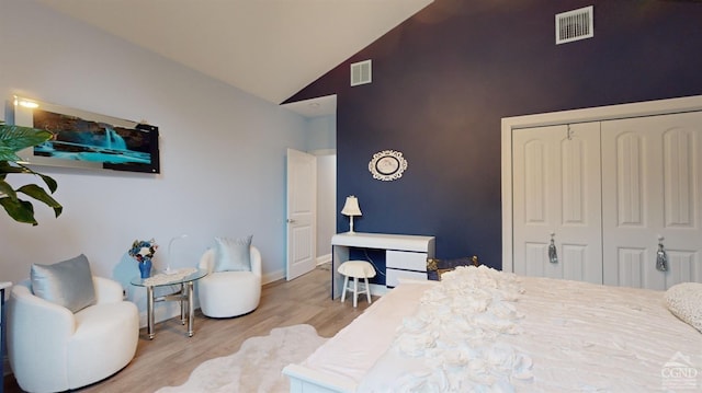 bedroom featuring light hardwood / wood-style floors, high vaulted ceiling, and a closet