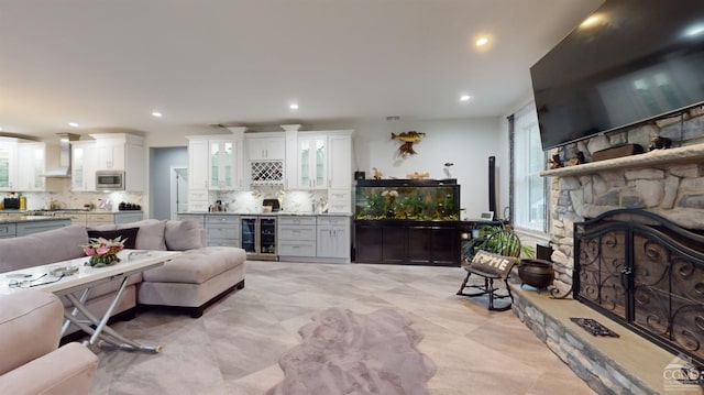 living room with bar area, a stone fireplace, and beverage cooler