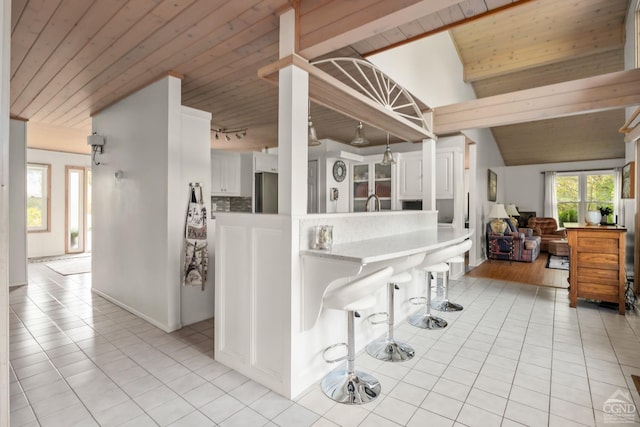 kitchen featuring white cabinets, vaulted ceiling with beams, and wood ceiling