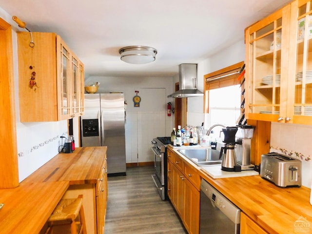 kitchen with dark wood-type flooring, sink, wall chimney exhaust hood, butcher block countertops, and stainless steel appliances