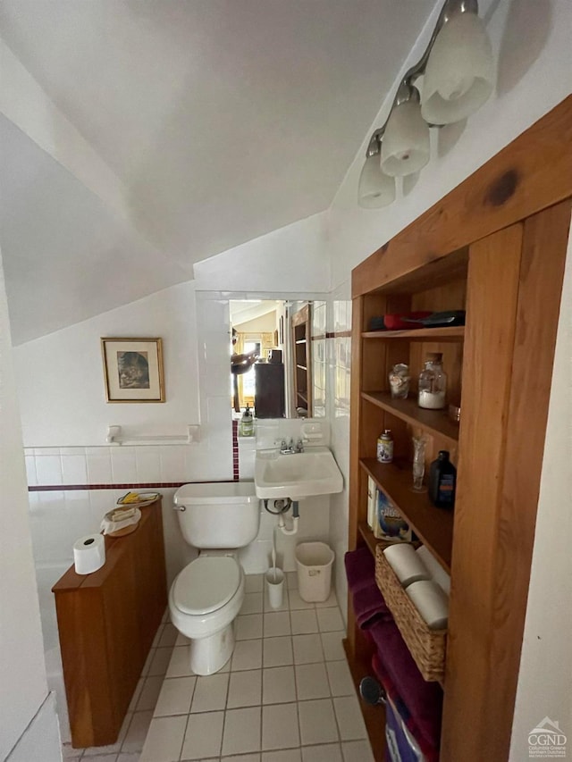 bathroom featuring sink, tile patterned flooring, lofted ceiling, toilet, and tile walls