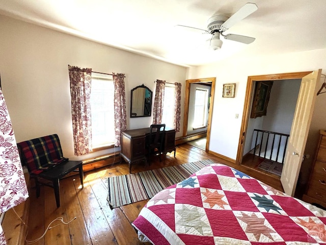 bedroom featuring baseboard heating, ceiling fan, and hardwood / wood-style floors