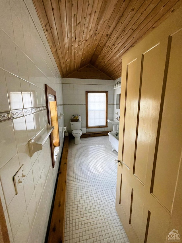 interior space featuring sink, wooden ceiling, lofted ceiling, toilet, and tile walls