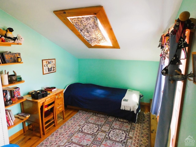 bedroom with vaulted ceiling with skylight and light hardwood / wood-style flooring