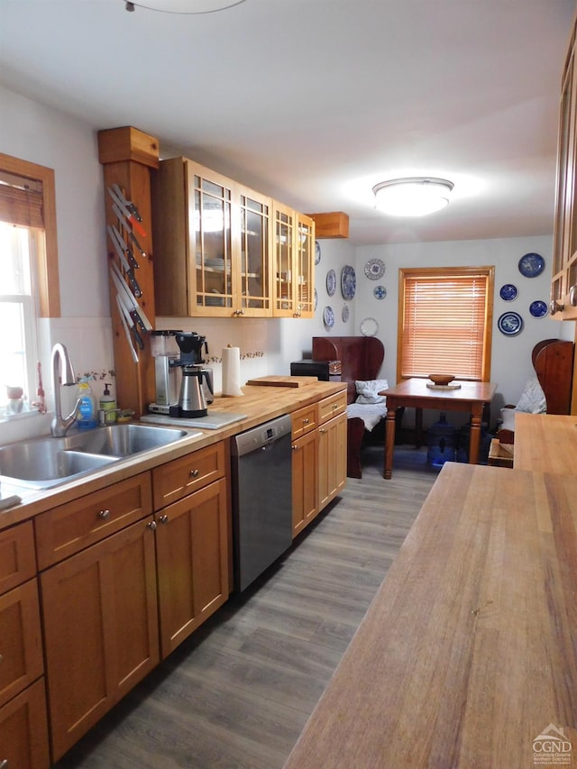 kitchen with stainless steel dishwasher, butcher block countertops, wood-type flooring, and sink