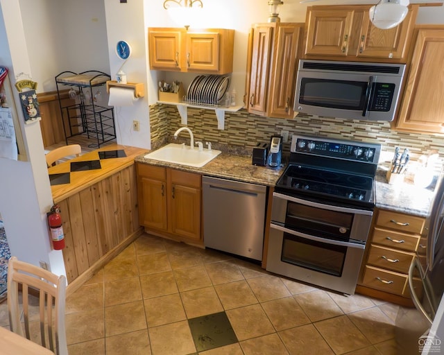 kitchen with light stone countertops, appliances with stainless steel finishes, tasteful backsplash, and sink