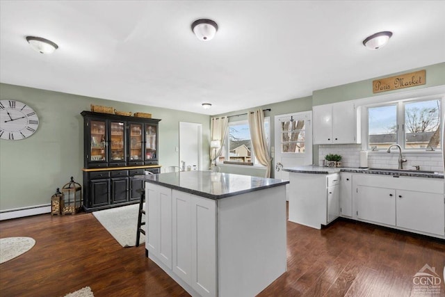 kitchen featuring a kitchen island, a wealth of natural light, white cabinets, and backsplash