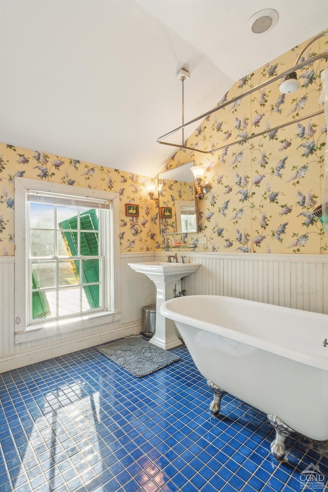 bathroom featuring tile patterned flooring, a tub, lofted ceiling, and sink