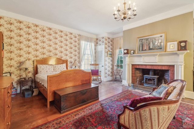 bedroom with wood-type flooring, a wood stove, and an inviting chandelier