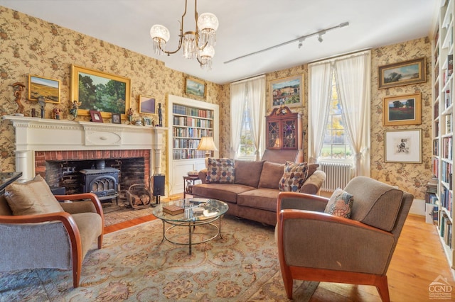 living area with light wood-type flooring, track lighting, a wood stove, and a notable chandelier