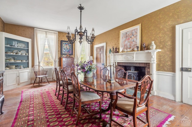 dining area with a wood stove, light hardwood / wood-style floors, and a notable chandelier