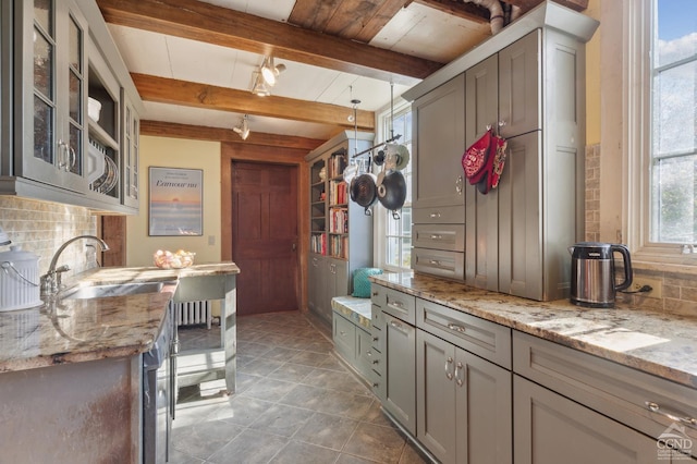 interior space featuring decorative backsplash, light stone counters, gray cabinetry, beam ceiling, and hanging light fixtures