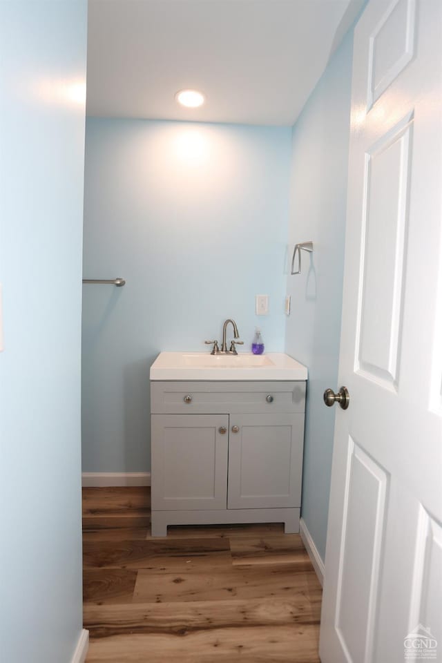 bathroom with recessed lighting, baseboards, wood finished floors, and vanity