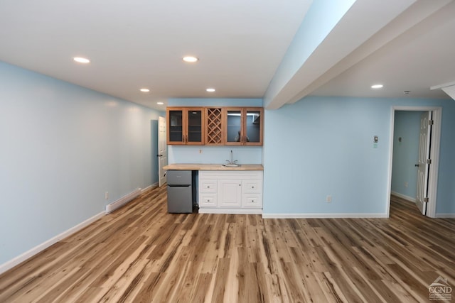 bar with a baseboard radiator, recessed lighting, wood finished floors, fridge, and wet bar