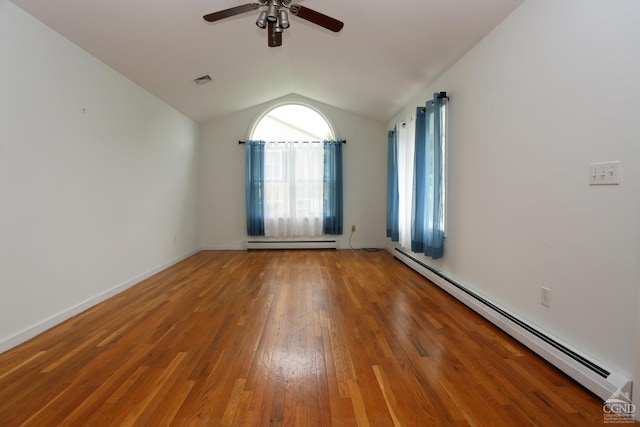 spare room with lofted ceiling, baseboard heating, wood finished floors, and baseboards