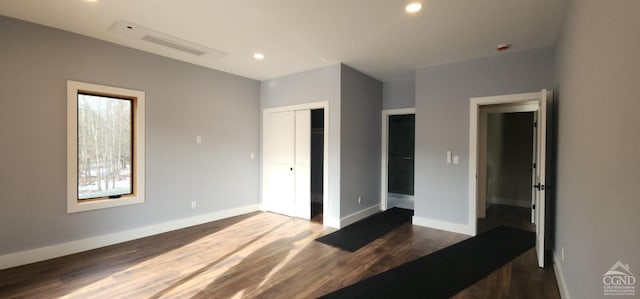 unfurnished bedroom featuring a closet and dark hardwood / wood-style flooring